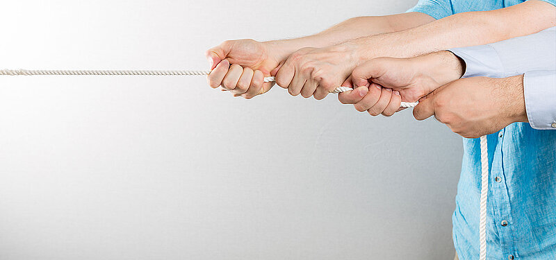 Mehrere Hände ziehen an einem Seil